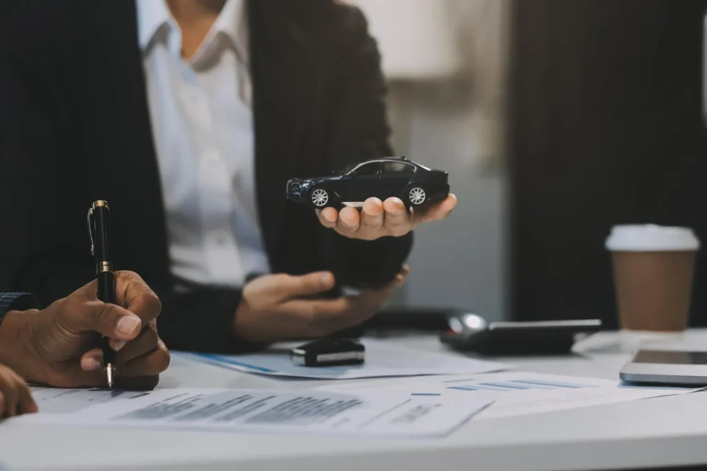 Pessoa segura miniatura de carro, discutindo multas após vender o carro e não transferir.