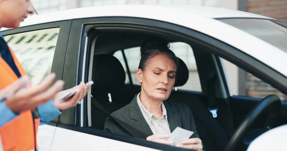 Mulher preocupada no carro recebe orientação sobre como indicar condutor para multa de veículo da empresa.