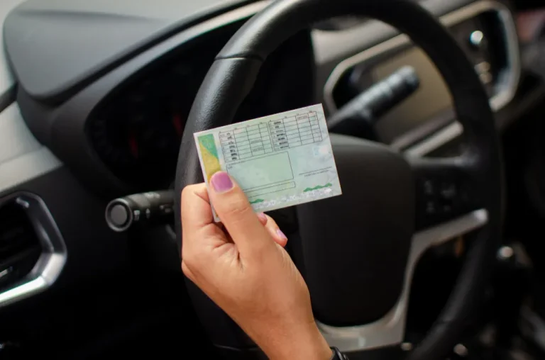 Mão segurando documento de CNH dentro de um carro, explicando o que é indicação judicial de condutor.