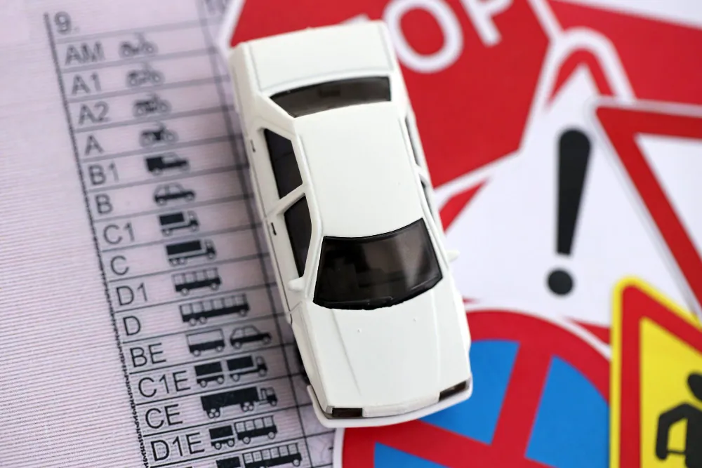 Miniatura de carro sobre lista de categorias de habilitação e placas de trânsito, como um advogado de trânsito fortaleza.