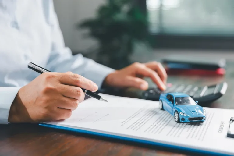 Pessoa escrevendo em documento com miniatura de carro, sobre como bloquear um carro vendido não transferido.