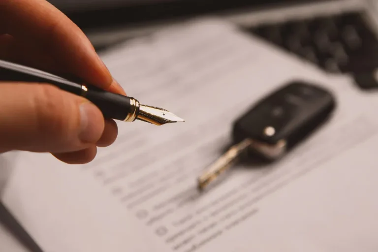 Mão com caneta sobre documento e chave de carro, sobre o que fazer se vendi um veículo e não foi transferido.